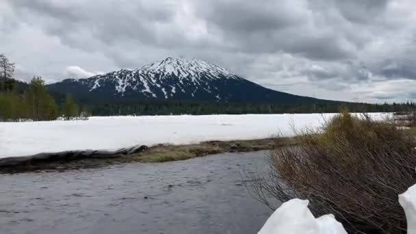 白雪覆盖的本山 前面是冰雪覆盖的斯帕克斯湖 前面是一条流淌的河流 在寒冷的阴天拍摄 美国俄勒冈州Nr Bend的Cascade Lake Scenic Byway — 图库视频影像