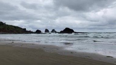 Point of view standing on the shoreline at Indian Beach facing the waves and the rock stacks on an overcast, stormy day - Ecola State Park, Oregon, USA