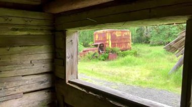 Looking through a wooden barn window at the abandoned Kestner Homestead to view a rusty vintage truck in a state of decay - Nr Quinault, Washington, USA