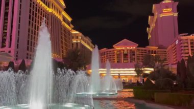 Las Vegas, Nevada, ABD - 03.25.2024: Caesars Palace Hotel ve Casino 'nun dış yüzeyi geceleyin ön planda güzel fıskiyelerle aydınlatıldı