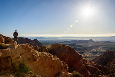 Erkek bir yürüyüşçü Las Vegas 'ın göz kamaştırıcı manzarasına bakan bir dağ zirvesinde güvenle duruyor - Red Rock Ulusal Koruma Alanı, Nevada, ABD