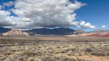 Ana park yolunda giden arabalı gökkuşağı renkli dağların manzarası. Sahnenin üzerindeki bulutlar - Red Rock Canyon Ulusal Koruma Alanı, Nevada, ABD