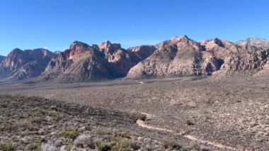 Kızıl Kaya Kanyonu Ulusal Koruma Alanı 'ndaki tüm manzaranın görüntüsü. Etrafı dağlarla çevrili çöl bitkileri ve Nevada, ABD 'den geçen park yolu.