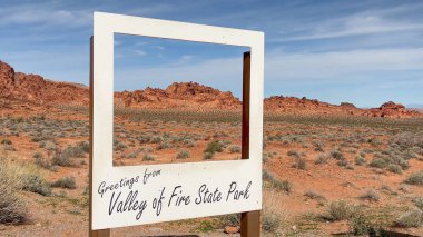 Fire State Park Vadisi, Nevada, ABD - 02.23.2024: Turistlerin poz vermeleri, fotoğraf çekmeleri ve güzel kırmızı kaya arka planıyla selfie çekmeleri için eğlenceli bir ahşap çerçeve.