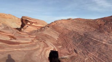 Bir kadın yürüyüşçü, Ateş Dalgası 'nın çarpıcı jeolojik kaya oluşumunda yürüyor. Şeritleri ve kum taşı katmanlarıyla ünlüdür - Fire State Park Vadisi, Nevada, ABD