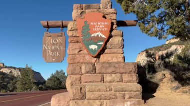 Zion Ulusal Parkı 'nın doğu girişindeki tabelayı kapatın. Mavi gökyüzü ile güzel bir gün. İşaret taş ve ahşaptan yapılmıştır. Utah, ABD 'de bir yol kenarında yer almaktadır.