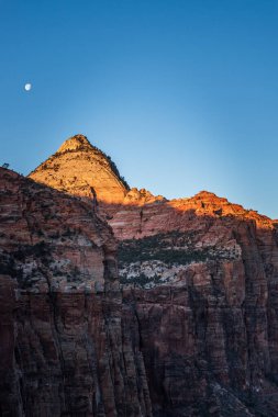 Güneş doğarken Utahs Zion Ulusal Parkı 'nda ay ışığı altında Zion Canyon Kayalıkları' nın nefes kesici manzarası. Sabahın erken saatlerinde kayalık kayalıklarda çarpıcı bir parıltı oluşur.