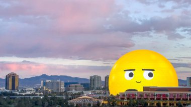 Las Vegas, Nevada, USA - 03.25.2024: The amazing yellow side eye face emoji display on the Las Vegas Sphere at sunset. clipart