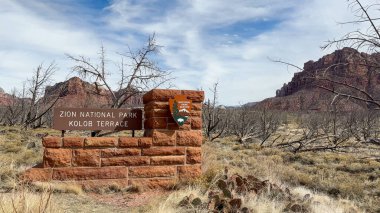 Virgin, Utah, ABD - 02.26.2024: Zion Ulusal Parkı Kolob Terası giriş işareti. Arka planda kırmızı kaya dağları ve kanyonlarla ulusal park manzarası.