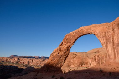 Moab, Utah 'taki nefes kesici Corona Kemeri' nde güzel bir gündoğumu ışıltısı. Daha geniş bir çöl manzarasının doğal güzelliğini ve eşsiz kaya oluşumlarını kusursuz bir şekilde yansıtıyor.