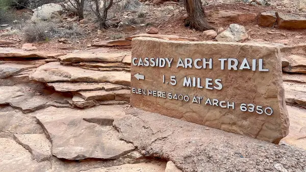 stock image A sign at the Cassidy Arch Trailhead at Capitol Reef National Park in Utah, USA. The sign indicates that the trail is 1.5 miles long. It also shows the starting and ending elevation - USA