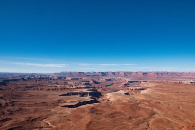 Utah 'taki Canyonlands Ulusal Parkları' ndan çarpıcı geniş açılı manzara. Uçsuz bucaksız, kurak manzaralar, derin kanyonlar ve berrak mavi gökyüzü nefes kesici ve huzurlu bir doğal manzara sunuyor.