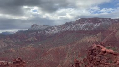 Moab, Utah 'taki kızıl kaya oluşumlarının güzel manzarası. La Sal Dağları karla kaplı arka planda görkemli bir şekilde yükselir. Gökyüzü bulutlu, dramatik bir atmosfer yaratıyor - ABD
