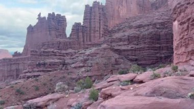 Parçalı bulutlu bir günde Moab, Utah yakınlarındaki güzel Fisher Kuleleri kaya oluşumları yavaş yavaş yükseliyor. Bu ikonik kırmızı kumtaşı kuleleri dağcılar ve yürüyüşçüler arasında popülerdir.