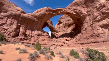 Bir kadın yürüyüşçü, ABD 'nin Utah eyaletinin Moab kenti yakınlarındaki Arches Ulusal Parkı' nda popüler bir kumtaşı kemeri oluşumu olan Double Arch 'ın altındaki ölçeği temsil ediyor. Büyük kırmızı kaya oluşumu onu cüce gibi gösteriyor..