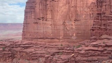 Moab, Utah 'taki Fisher Kuleleri' nde yüksek bir yamaç yamacına yavaşça eğiliyor. Alttaki küçük bir yürüyüşçü çarpıcı kırmızı kaya oluşumlarının büyüklüğünü gösteriyor.