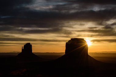 Arizona, Anıt Vadisi 'nde nefes kesen gündoğumu, ikonik Mittens kaya oluşumlarının çarpıcı siluetlerini mercek patlaması ile sunuyor. Bu manzara Amerika 'nın güneybatısının güzelliğini yansıtıyor..