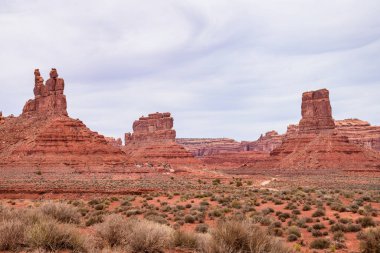Tanrıların Vadisi 'nin güzel manzarası etkileyici popolar ve kırmızı kaya oluşumları sergiliyor. Bulutlu bir günde yakalanan bu görüntü Utah 'ın haşin, doğal güzelliğini vurguluyor.
