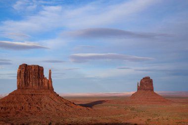 Arizona, ABD 'deki Monument Valley Mittens panoramik manzarası. İkonik kırmızı kumtaşı popolar, Amerika 'nın güneybatısının büyüleyici manzaralarını temsil eden mavi gökyüzüne karşı görkemli bir şekilde dururlar..