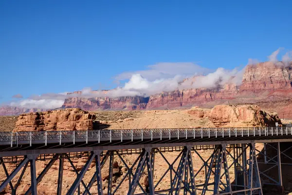 Arizona 'daki manzaralı Vermillion uçurumlarına karşı Iconic Navajo Köprüsü. Yakaladığımız görüntülerde köprü yapısı, çarpıcı arazi ve alçak bulutlar kayalıkların üzerinde yuvarlanıyor.