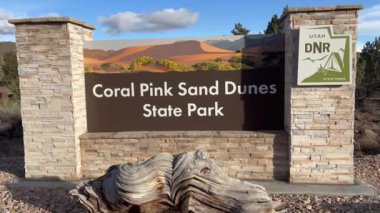 Kanab, Utah, ABD - 03.17.2024: The Coral Pink Sand Dunes State Park giriş işareti. Arka planda bulutlar olan güzel mavi bir gökyüzü. Utah 'ta seyahat ve turizm projeleri için mükemmel..