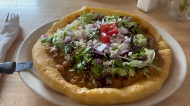 Arizona 'da bir restoranda servis edilen, fasulye, marul, domates, peynir ve soğanlı geleneksel Amerikan kızarmış ekmeği Navajo Taco' nun yakın plan çekimi. Taze ve lezzetli malzemeler - ABD 