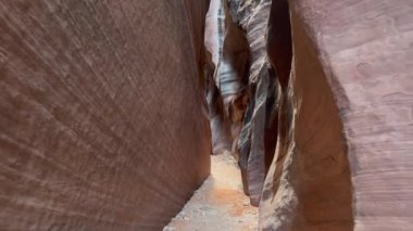 ABD 'nin Utah kentindeki Wire Pass dar kum taşı kanyonu boyunca yapılan bir yürüyüşün POV bakış açısı. Dar, pembe kanyonda kumlu bir patikada yürüyorum. Macera, seyahat ve turizm.