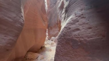 Bir yürüyüşçünün bakış açısı Arizona, Utah sınırındaki Wire Pass Kanyonu 'nun dar kumtaşı duvarlarından geçiyor. Güzel güneş ışığı, kanyon duvarlarına gölge düşürüyor.