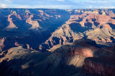 Göz kamaştırıcı bir gün batımı Arizona 'daki Grand Canyon Ulusal Parkları' na sıcak bir ışık tutuyor. Geniş görünüm, bu ikonik manzaranın karmaşık kaya oluşumlarını ve gölgelerini sergiliyor.