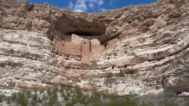 Arizona 'daki Montezuma Şatosu Ulusal Anıtı' nın alçak açılı görüntüsü. Antik Sinagua uçurum evleri kireçtaşı bir oyuğun içine inşa edilmiştir. Beyaz bulutlar üzerimizdeki mavi gökyüzünü işaret ediyor.