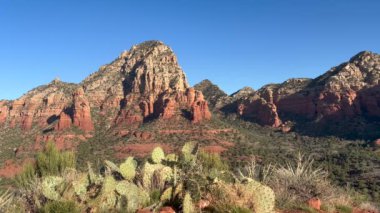 Sedona, Arizona 'daki Sugarloaf Dağı' ndan Capitol Butte ve etrafındaki kızıl kaya dağlarının manzarası. Güzel manzara dikenli armut kaktüsünü, çöl faunasını ve açık mavi gökyüzünü kapsar.