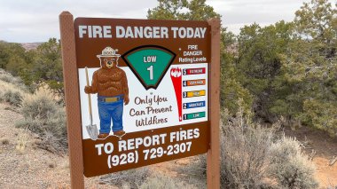 Kayenta, Arizona, ABD - 03.12.2024: Arizona, ABD 'de çöl manzarasında düşük yangın tehlikesini gösteren bir tabela üzerinde Smokey the Bear. Bu, orman yangını sezonunda güvenlik ve ihtiyatı çağrıştırıyor..