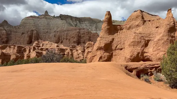 Utah, ABD 'deki Kodachrome Havzası' ndaki çarpıcı kırmızı kaya oluşumları ve kum tepelerinin manzarası. Dramatik manzarada yüksek kum taşı kayalıkları ve eşsiz kaya oluşumları yer almaktadır..