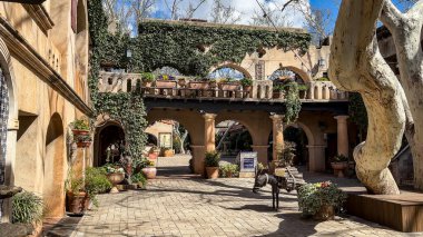 Sedona, Arizona, USA - 03.20.2024: A beautiful courtyard in Tlaquepaque Arts and Shopping Village in Sedona. The courtyard features Spanish colonial architecture, with arches and stucco walls. clipart