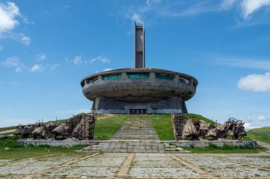 Benzersiz terk edilmiş Buzludzha Anıtı, yemyeşil yemyeşil ve parlak gökyüzüne karşı kurulmuş bir Sovyet tasarımıyla Bulgaristan ve Avrupa
