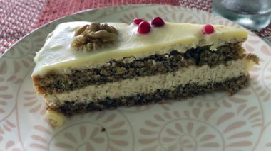Ceviz ve kırmızı frenk üzümlü beyaz çikolata ganache ile süslenmiş bir dilim lezzetli Bulgar cevizli keki. Lezzetli bir ikram, her durum için mükemmel..
