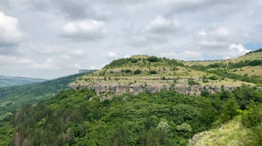 Bulgaristan 'ın Garga Bair Hill kentinin manzarası. Bereketli yeşil tepeler ve kayalık kayalıklar bulutlu bir gökyüzüne kavuştu - Veliko Tarnovo, Bulgaristan ve Avrupa