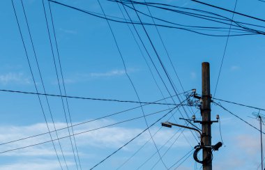 Bulutlu mavi gökyüzüne karşı dağınık kablolar içinde Lamppost