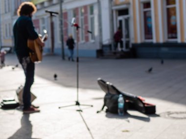 Güneşli bir günde yaya caddesinde akustik gitarlı sokak müzisyeninin odağından çıkmış görüntüsü. Ukrayna, Zhytomyr, Kasım 04, 2022