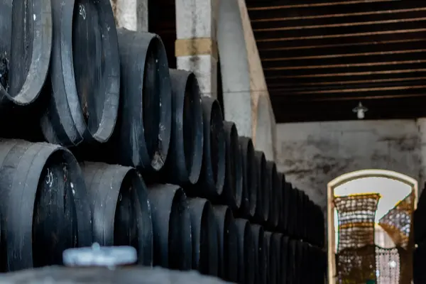 stock image Black wine barrels with wine in winery warehouse