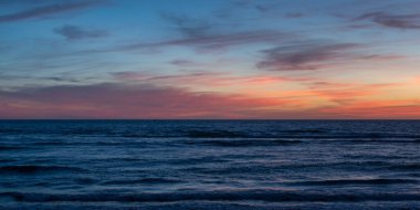 Okyanus kıyısının karanlık suları resimli günbatımı gökyüzünün arka planında