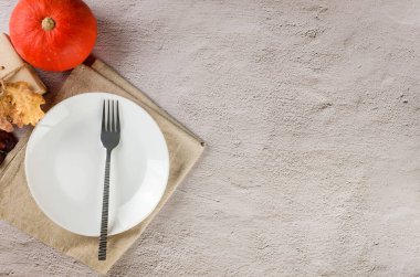 Şükran Günü ya da Cadılar Bayramı sofrası. Çatal bıçaklı, dökülen yapraklı ve el işi kağıdının içindeki boş beyaz tabağın üst görüntüsü. Olay masası dekorasyonu. Şükran Günü konsepti, sonbahar sofrası.