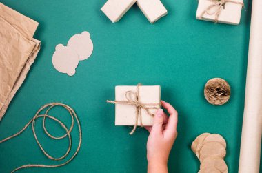 Noel arkaplanında hediye kutuları ve el işi kağıtları Wooman 'ın ellerinde. Tatil hazırlığı. Xmas bütçe tasarrufu. Sıfır atık kış dekoru tatili kavramı. 