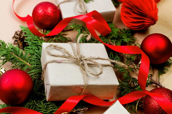 クリスマスの装飾の概念 クラフト紙 赤い泡 松の枝とベージュの背景にリボンで包んだトップビューのギフトボックス クリスマスのお祝い 冬の休暇の準備 — ストック写真