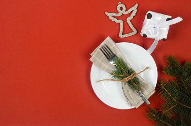 Noel arkaplanı boş bir tabak ve çatal bıçak seti ve kırmızı arka planda takılar. Yılbaşı yemeği konsepti, mesaj için boş yer.. 