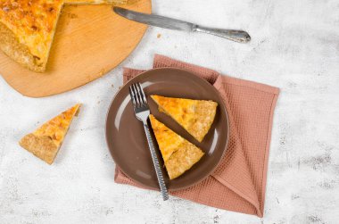 Geleneksel Fransız ev yapımı soğanlı turta veya kiş. Açık peynirli ve soğanlı turta açık gri masada.