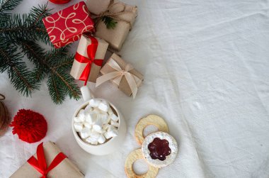 Sıcak kış içeceği. Noel sıcak çikolatası ya da marşmelovlu kakao, ışık arkaplanlı sandviç kurabiyeleri Noel süslemeleri ve hediye kutusu. Kış tatili kavramı.