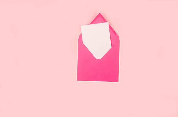 Minimal composition with pink envelope and white blank card on pink background. Mockup with envelope and blank card. The apartment lay. Greeting card or invitation mailing concept.