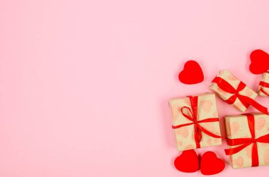 Kırmızı kalpler ve hediye kutuları el işi kağıdına ve pembe arka plana kırmızı kurdele bağlamış. Sevgililer Günü konsepti, düğünler, nişanlar, Anneler Günü, doğum günü. Metin için yeri olan tebrik kartı 