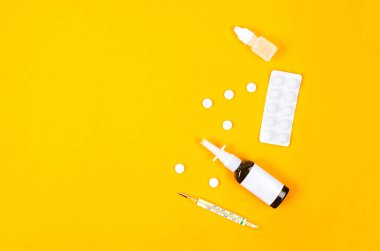 Medicines for treatment- pills, spray bottles, blister and thermometer on yellow background, Pharmaceuticals and medicine. Illness concept.